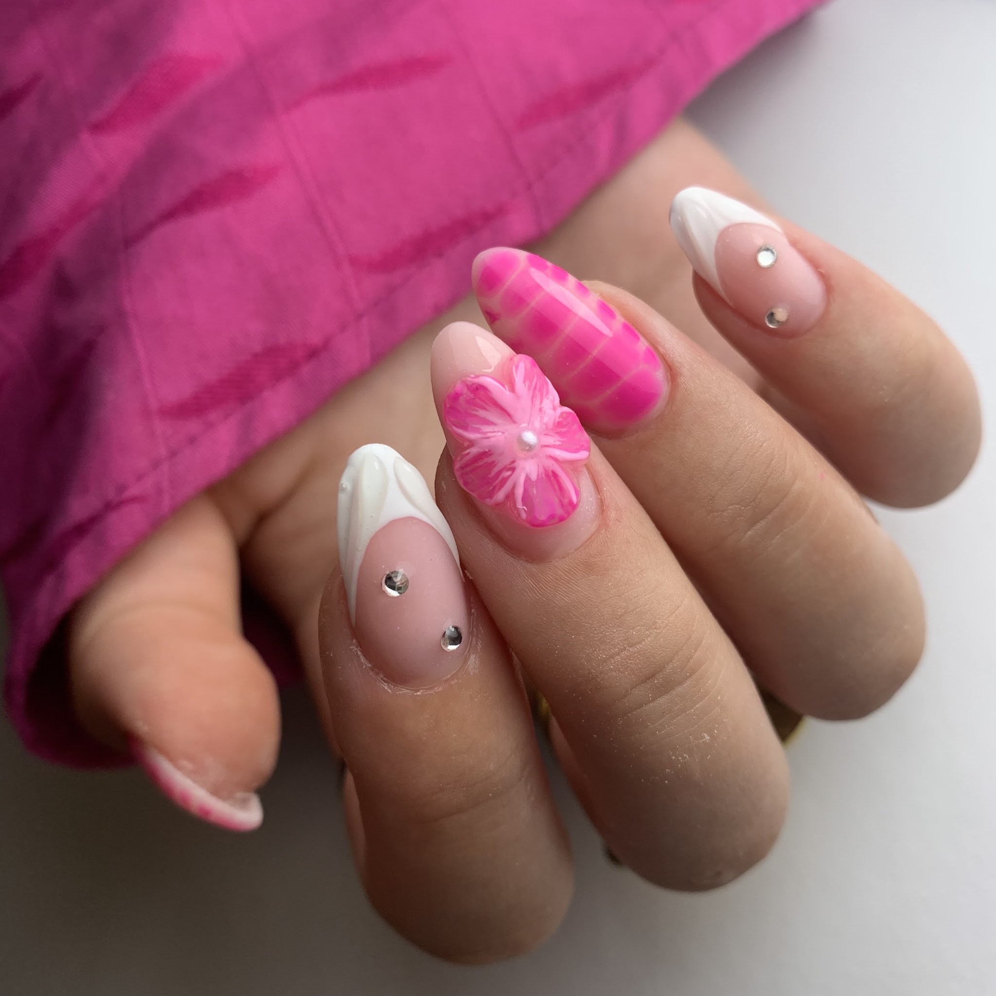 Roze en witte nagelkunst met een bloem, ruitjes en kleine steentjes
