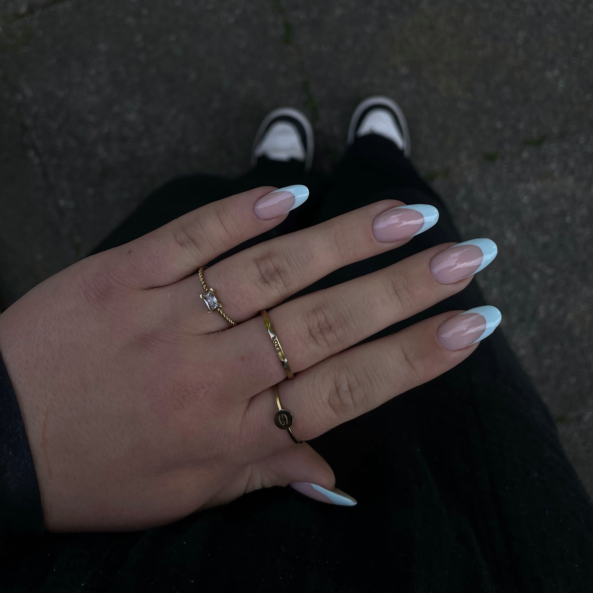 Lichtroze French-nagels gefotografeerd tegen donkere kleding